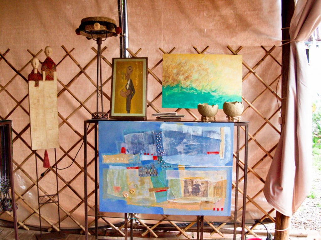 Artisan sculptures and colorful paintings on display under a pink canopy tent while shopping in Villa de Leyva.