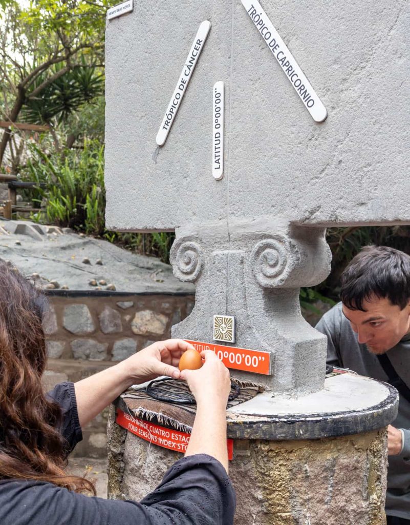 Tourists attempting to balance an egg on a nail directly on the Ecuador equator line at the Intiñan Museum a popular stop on many of the Middle of the World tours.