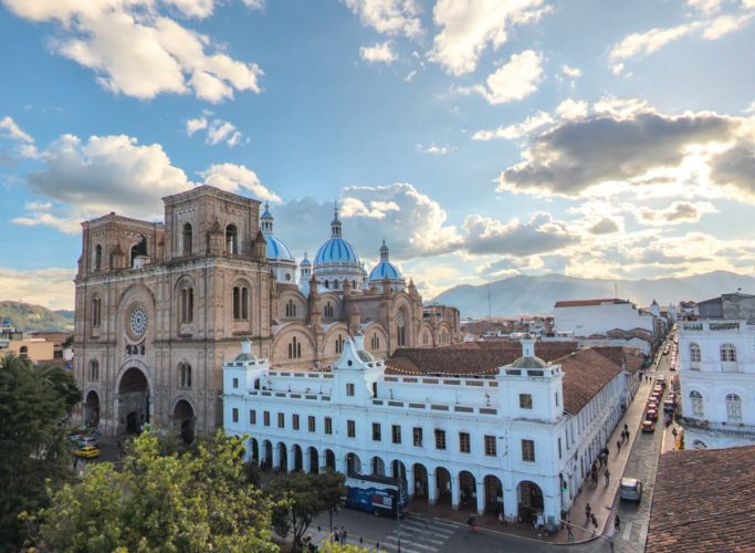 A wide view of Cuenca's Cathedral with its iconic blue domes under a dramatic sky. Visiting this landmark is one of the top things to do in Cuenca Ecuador.