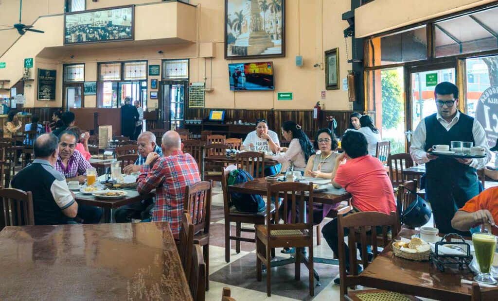 Customers fill the tables at Cafe La Habana in Mexico City for breakfast. The open air space features images of Cuba on the walls.