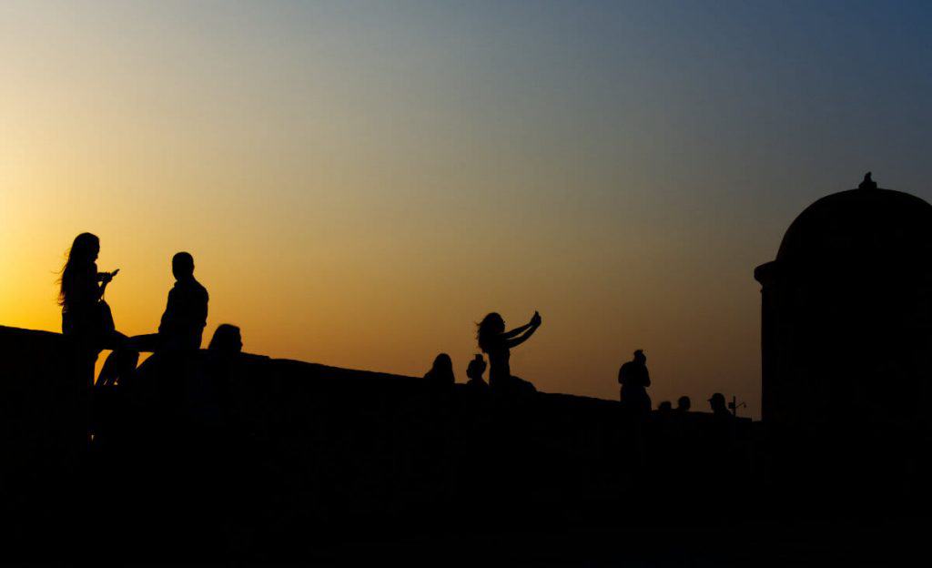 Various people sit on the wall to watch the sunset in Cartagena.