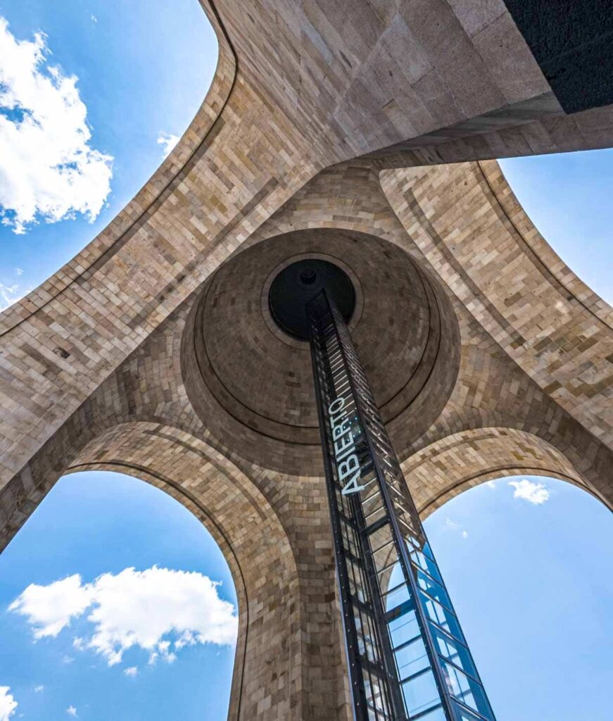 Close up view from underneath the Revolution Museum in Mexico City with blue sky in the background.