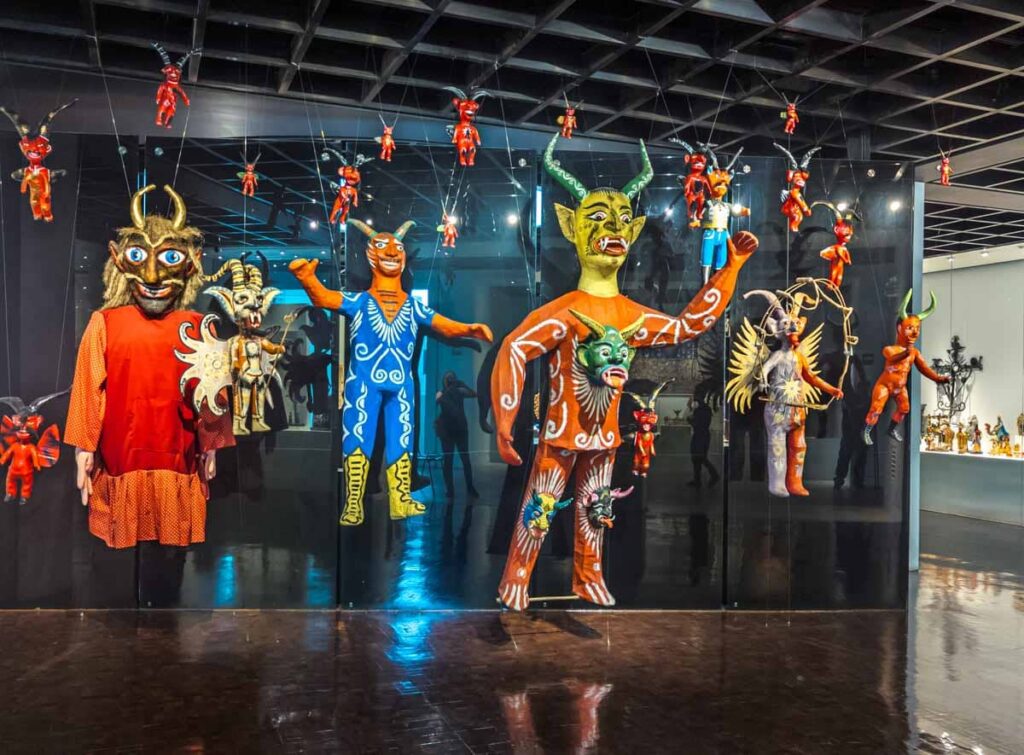 Several large and small figures on display at the Popular Art Museum in Mexico City featuring bright colors and animalistic design.
