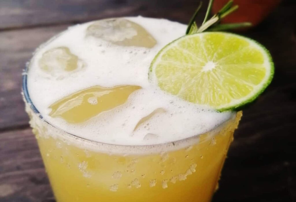 A margarita on ice in a glass rimmed with salt and topped with a lime slice at a cooking class Mexico City.