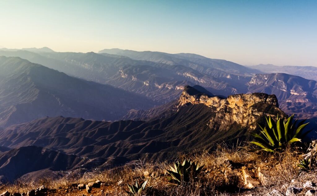 From Mirador Cuatro Palos, Queretaro long green valleys stretch out from the rugged mountaintop above. In the foreground is a large maguey plant soaking in the sun.