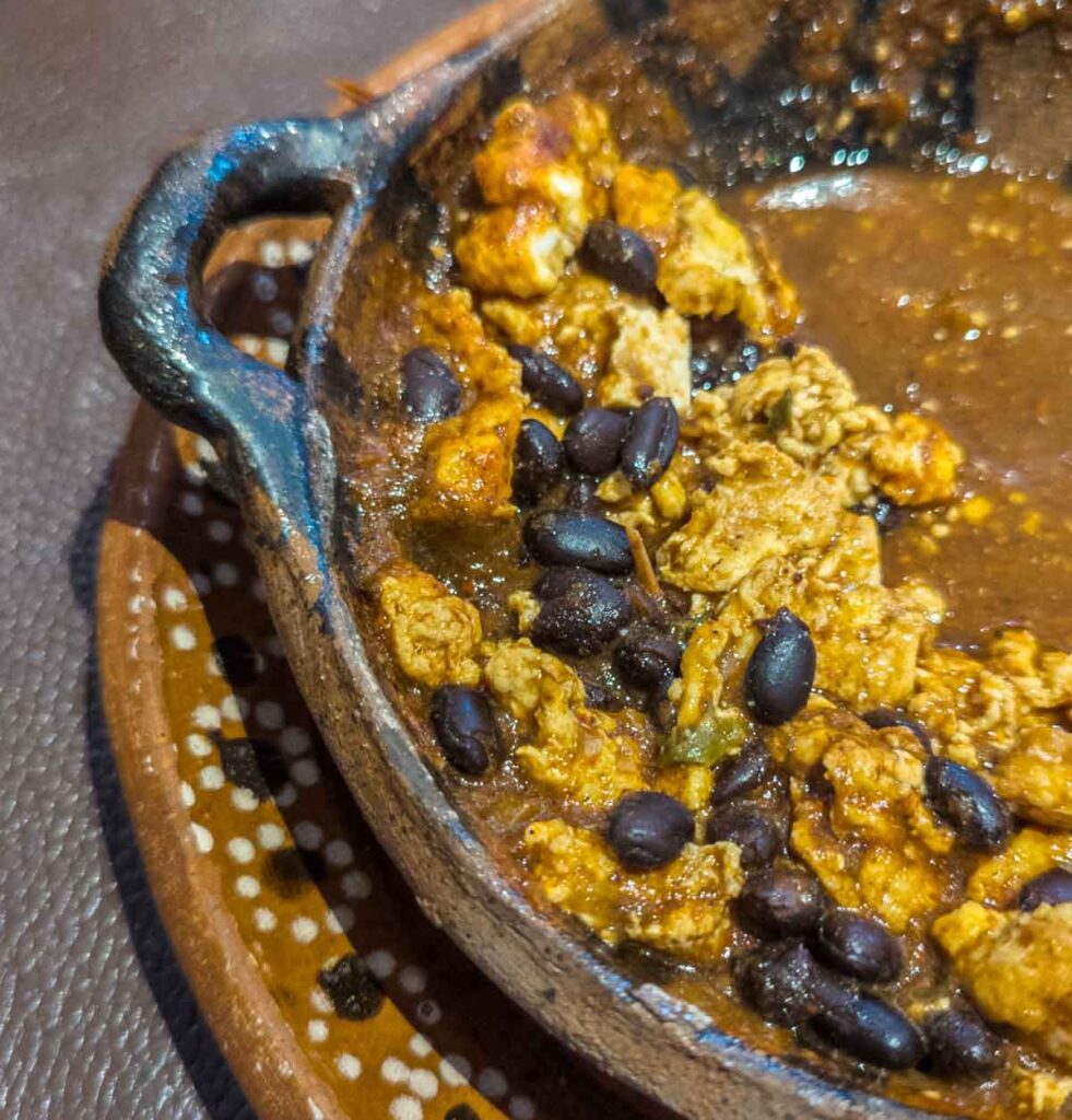 Scrambled eggs and black beans in a tomato sauce are served in a clay bowl at El Cardenal Restaurant, one of the top places to eat breakfast in Mexico City.