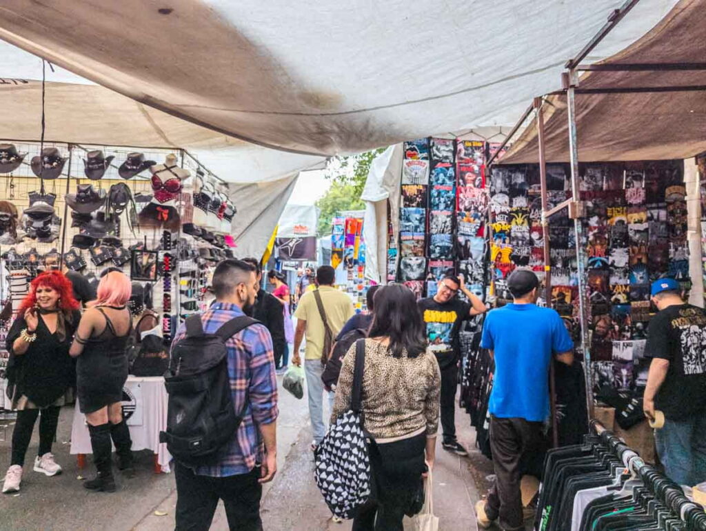 At El Chopo Market in Mexico City a few customers mingle and check out the products of different shops which include lots of black t-shirts.