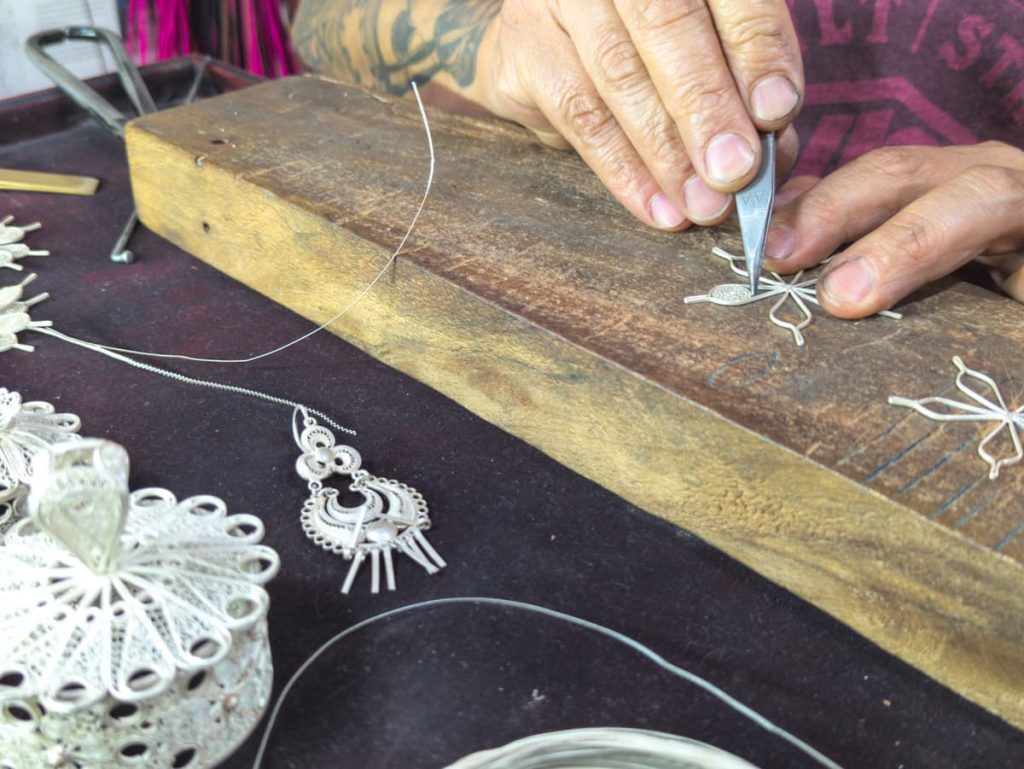 Close-up of a craftsman shaping intricate silver filigree jewelry by hand, a highlight of the artisan day tours from Cuenca, Ecuador.