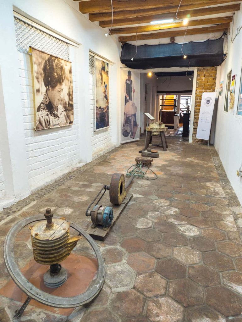 A hallway in one of the Panama hat museums in Cuenca showing vintage photos and old hat making equipment, part of an exhibit on traditional craftsmanship.