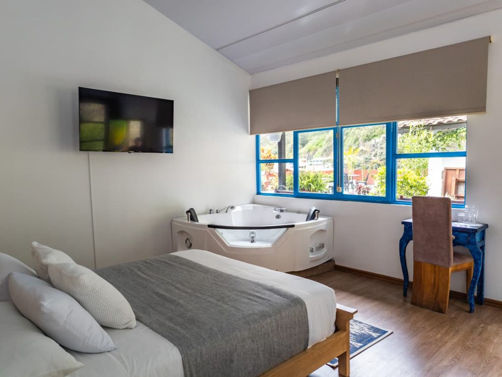 Inviting hotel room featuring a private in-room jacuzzi, modern decor, and large windows with lush mountain views at Hotel Mi Pueblo, one of the best places to stay in Baños, Ecuador.