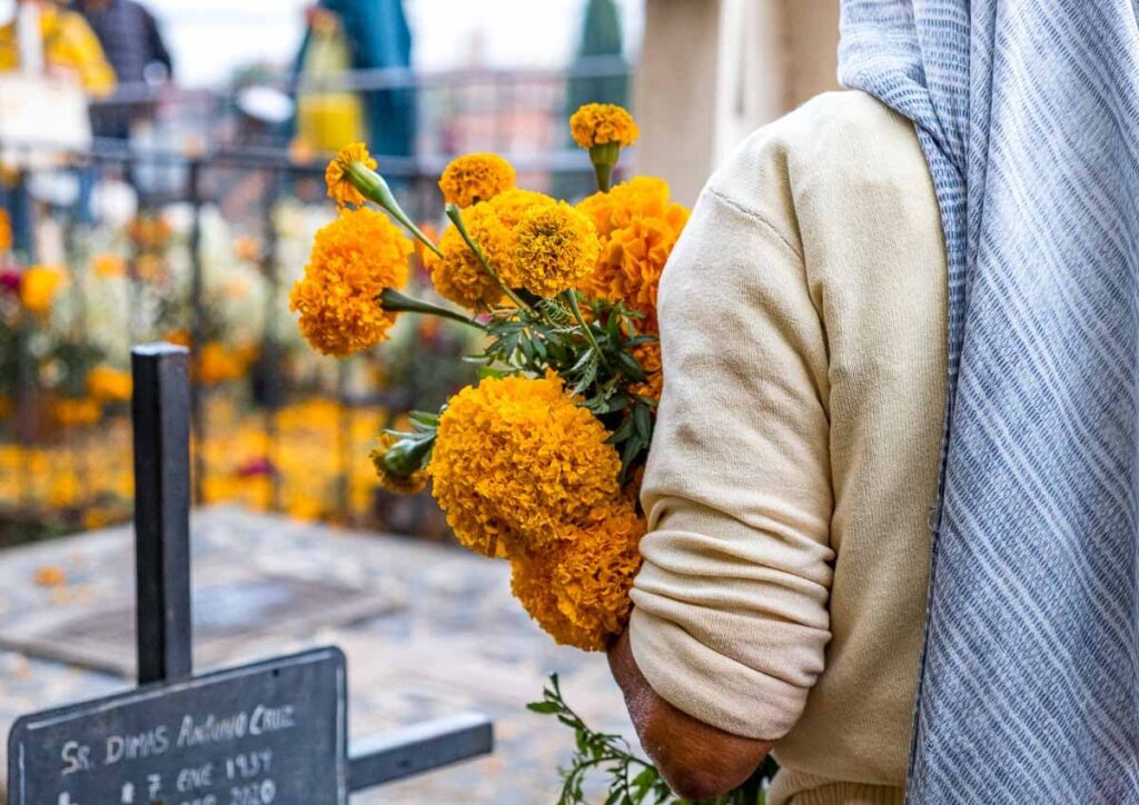 A person carrying yellow flowers on Dia De Muertos in Patzcuaro.
