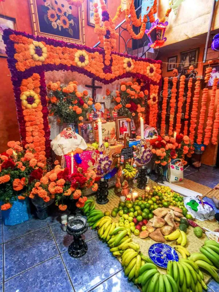 A Day of the Dead altar at Santa Fe Laguna Michoacan with orange flowers and a lot of fruits and food offered in front.
