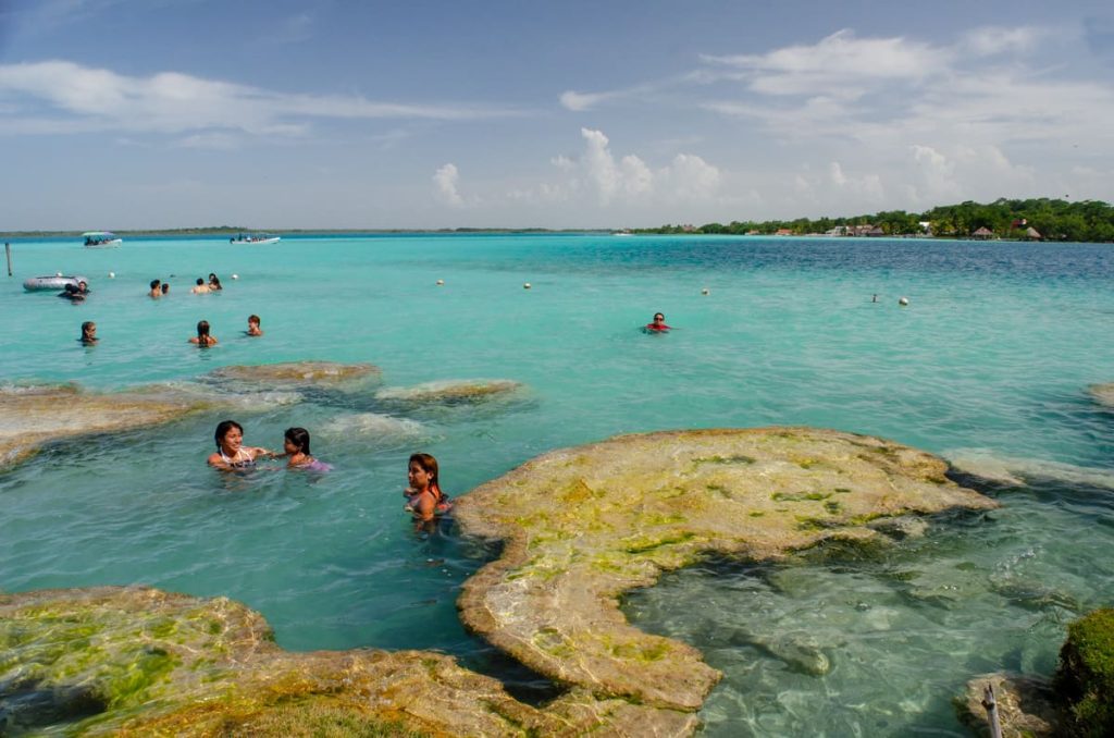 People swim in the crystal-clear, turquoise waters of Laguna Bacalar, one of the best places to visit in Mexico.