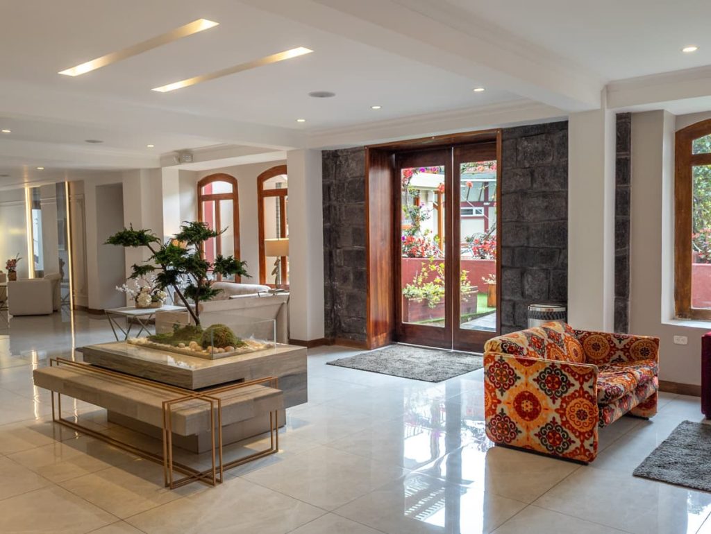 The lobby at Sangay Hotel, one of the best places to stay in Baños features contemporary furniture, polished tile floors, and a decorative bonsai garden centerpiece.