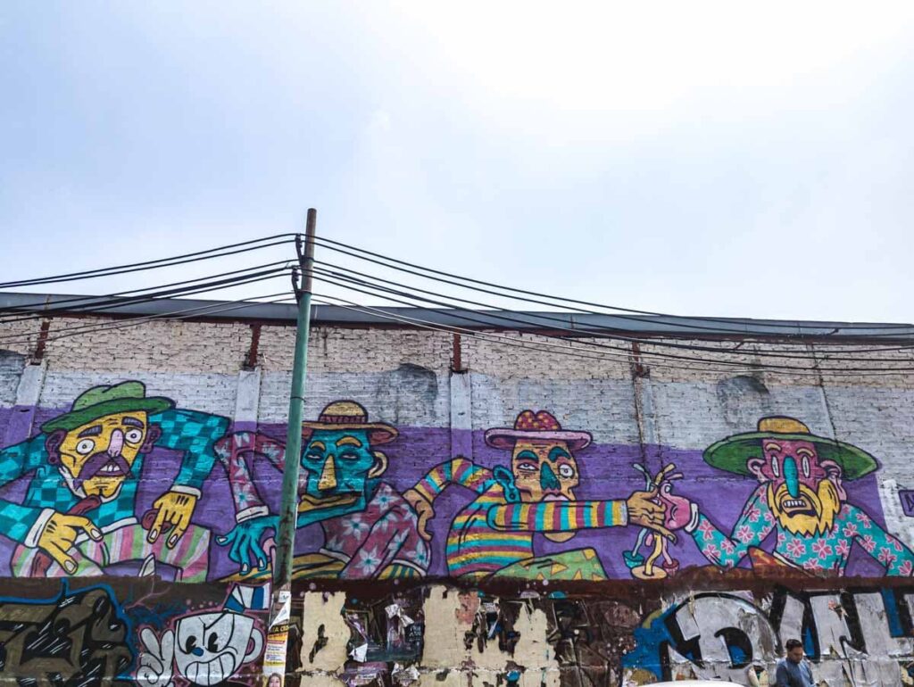 A street art in Doctores Mexico City depicts four men with weird head shapes and facial expressions holding colorful mushrooms.