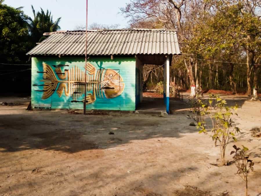 A bright turquoise house with a skeleton fish painted on the side and a tin roof, typical for the island.