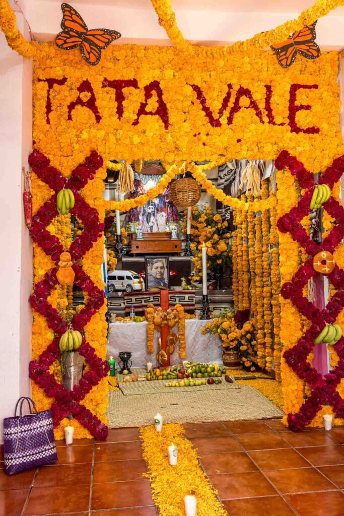 Family altar decorated with yellow and red flowers and food on the Day of the Dead in Patzcuaro.