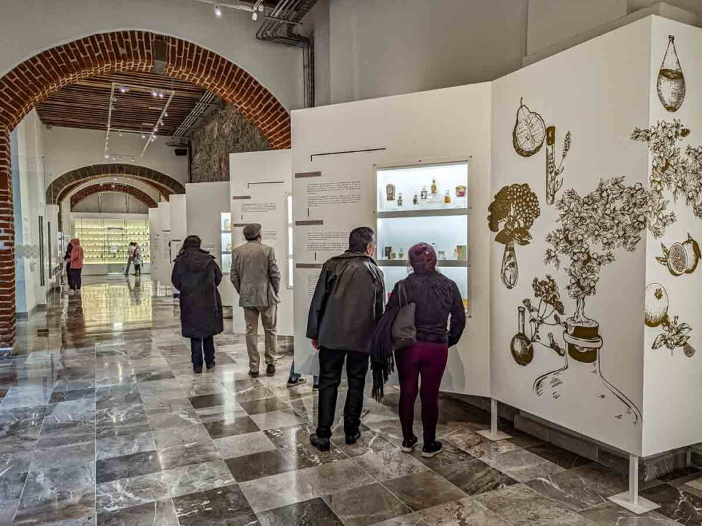 A few visitors at the Perfume Museum in Mexico City looking at the perfumes in the glass displays.