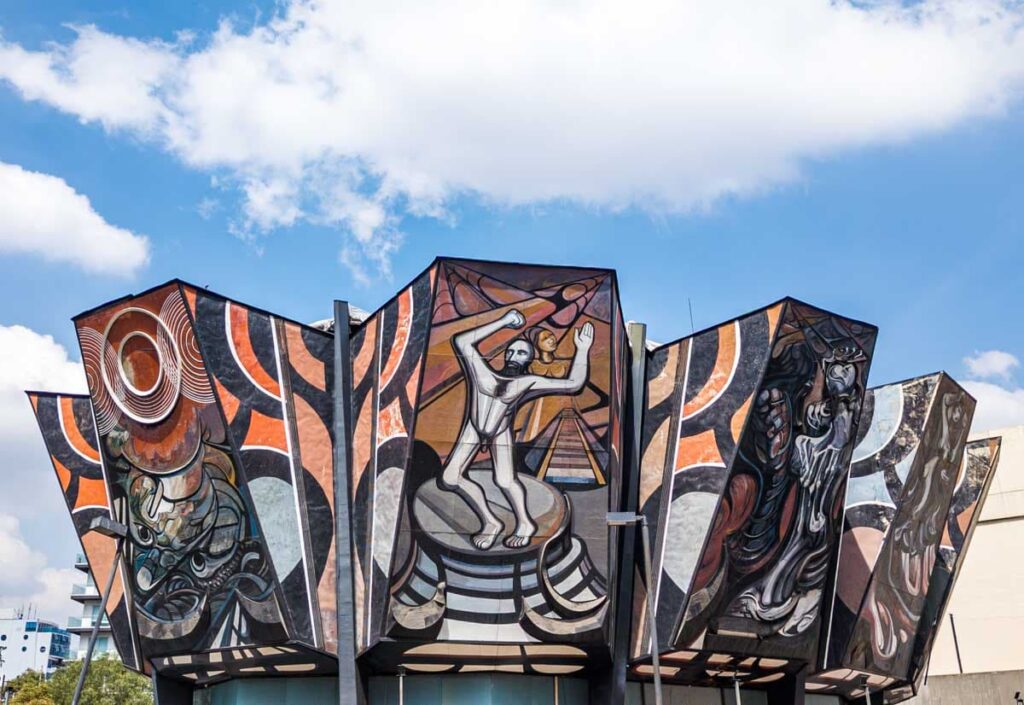 Exterior view of the Polyforum Siqueiros features huge murals under the blue sky with white clouds in CDMX.