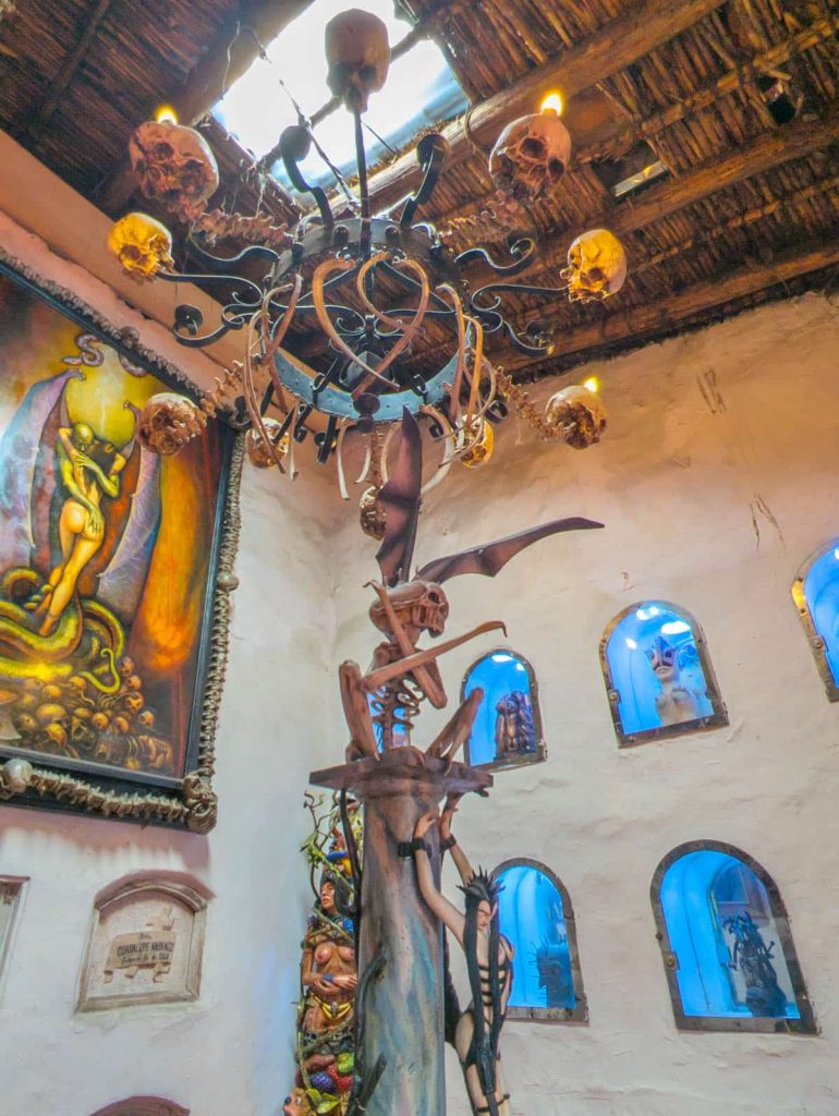 Interior of the Prohibido Centro Cultural showing surreal and extreme artwork under a chandelier adorned with faux skulls and bones.