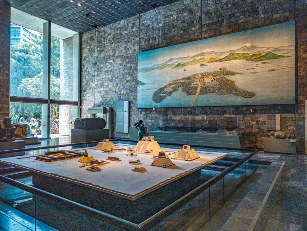 A replica of Teotihuacan at the Anthropology Museum in Mexico City near a large wall painting of the ancient city.