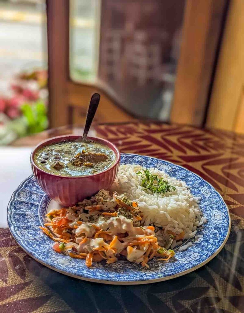 At one of the restaurants in Mindo Ecuador, a plate of rice, shredded carrot salad, and a small bowl of stew sits on a table for lunch.