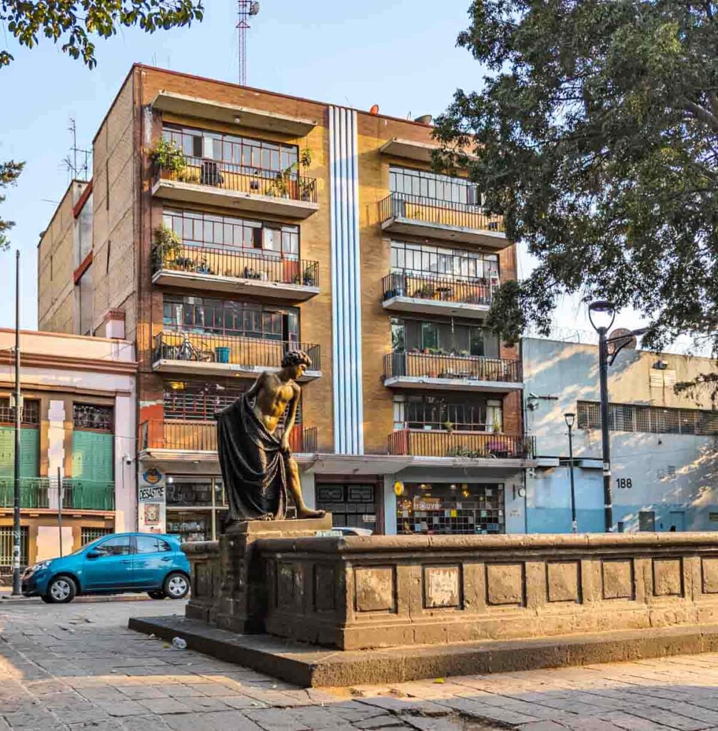 A statue of a man draped with a cloth in the center walking path along a road in Roma Note, one of the best neighborhoods in Mexico City.