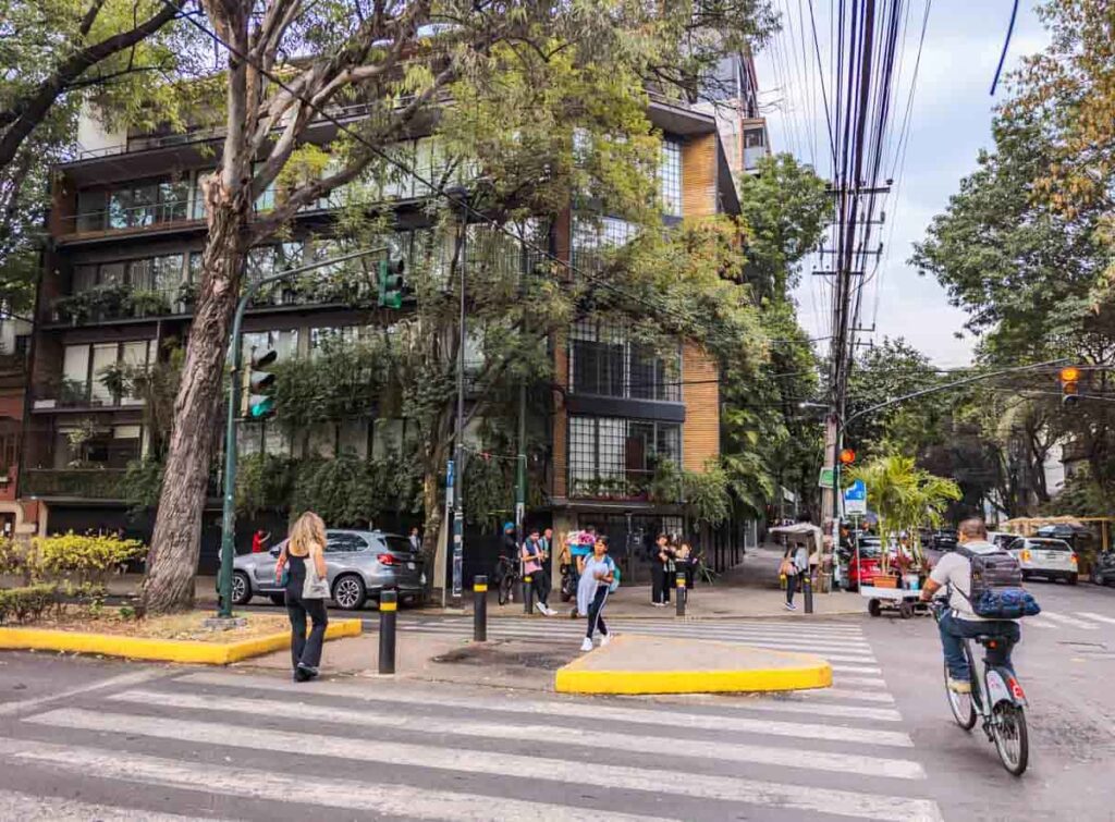 Pedestrians and a bicyclist cross an intersection in Roma Norte neighborhood of Mexico City, one of the best places to stay.