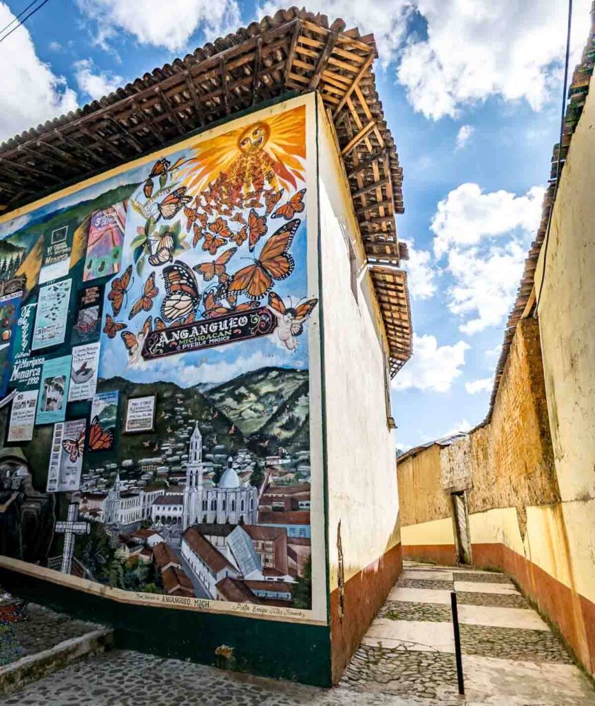 Street art of monarch butterflies flying to the sun at the town Angangueo Michoacan on the corner of a building.