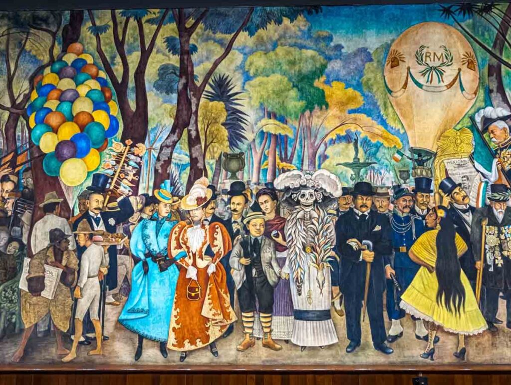 The Diego Rivera mural, Sunday Afternoon in Alameda Park in Mexico City depicts a catrina figure standing next to Rivera as a child with Frida Kahlo in the background. They are surrounded by many other figures from Mexican history.