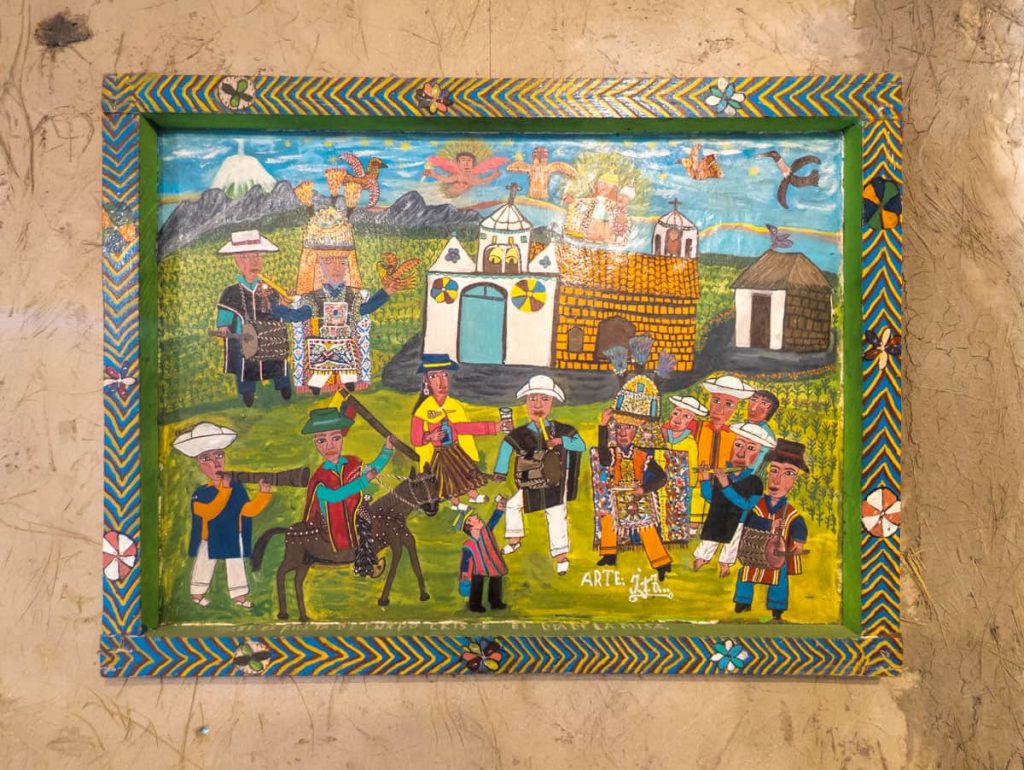 Inside a Cuenca museum, a vibrant folk painting from Tigua Ecuador depicts traditional Andean celebrations with musicians, dancers, and mountain scenery.