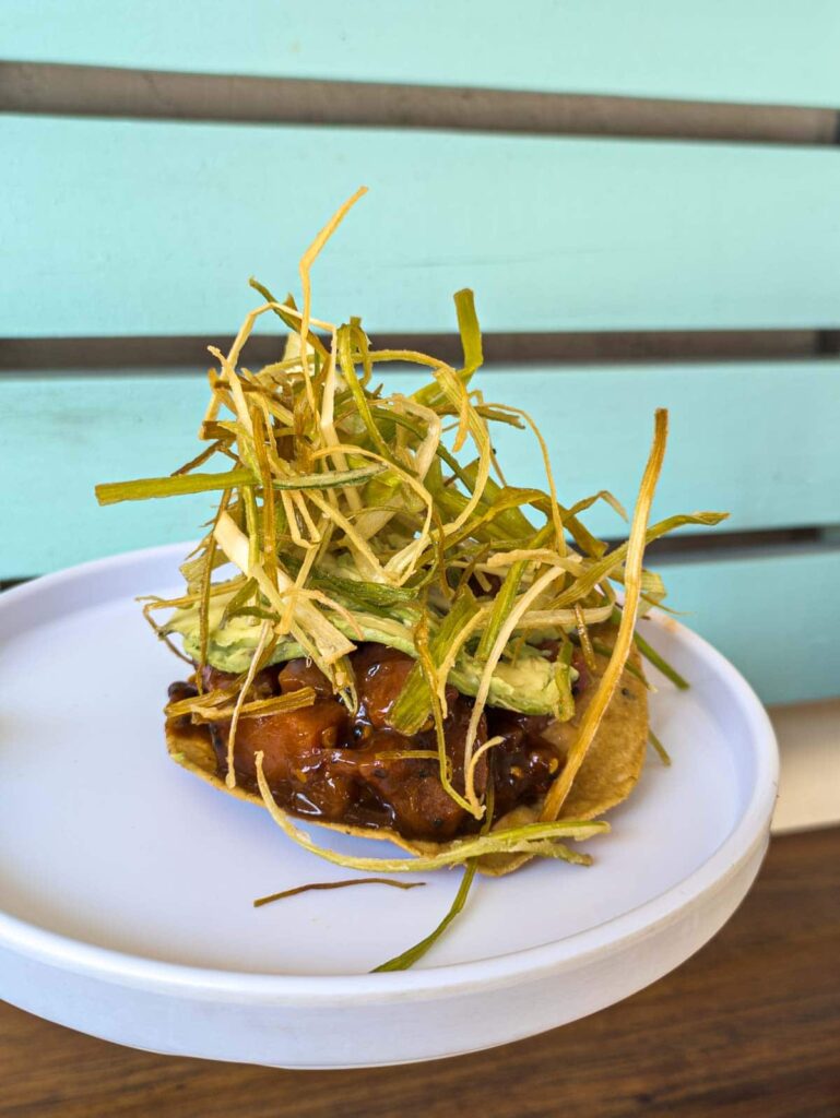 A tuna tostada topped with crispy fried onions served on a white plate at Maria Pescadora, one of the best seafood restaurants in Mexico City.