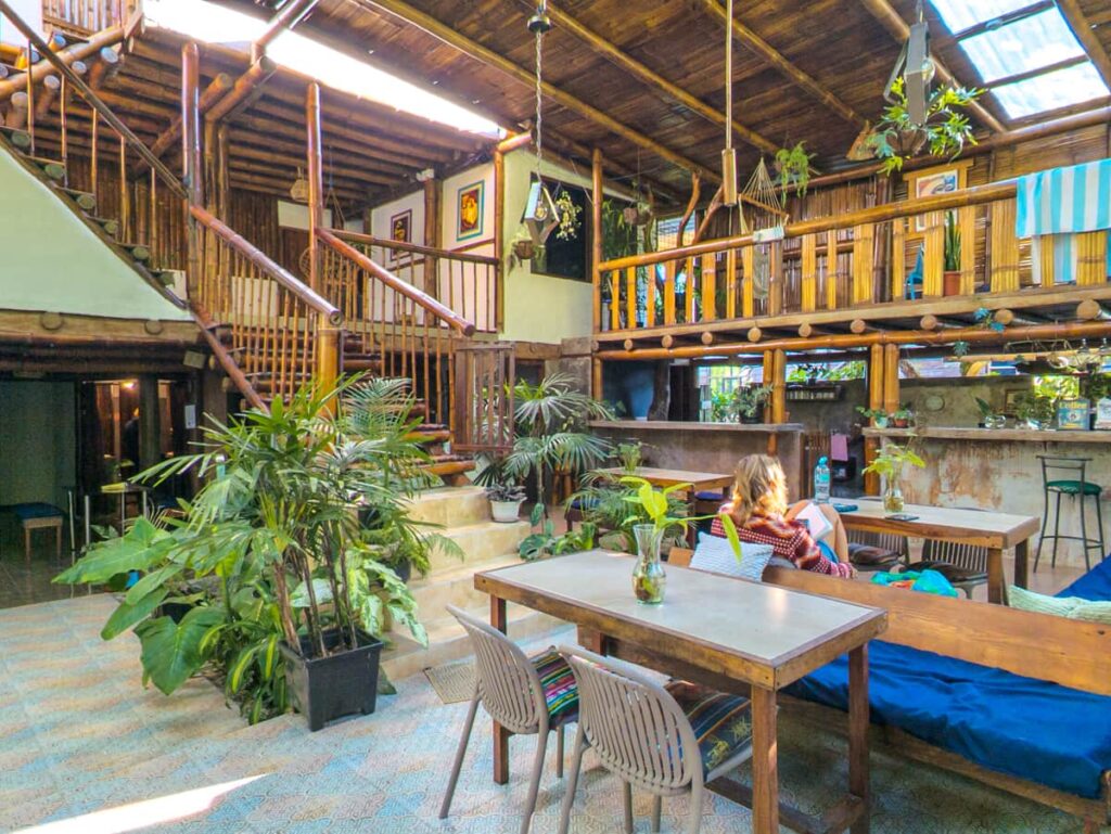 A woman reads a book in the common courtyard of a wooden hostel, one of the best places to stay in Mindo Ecuador.